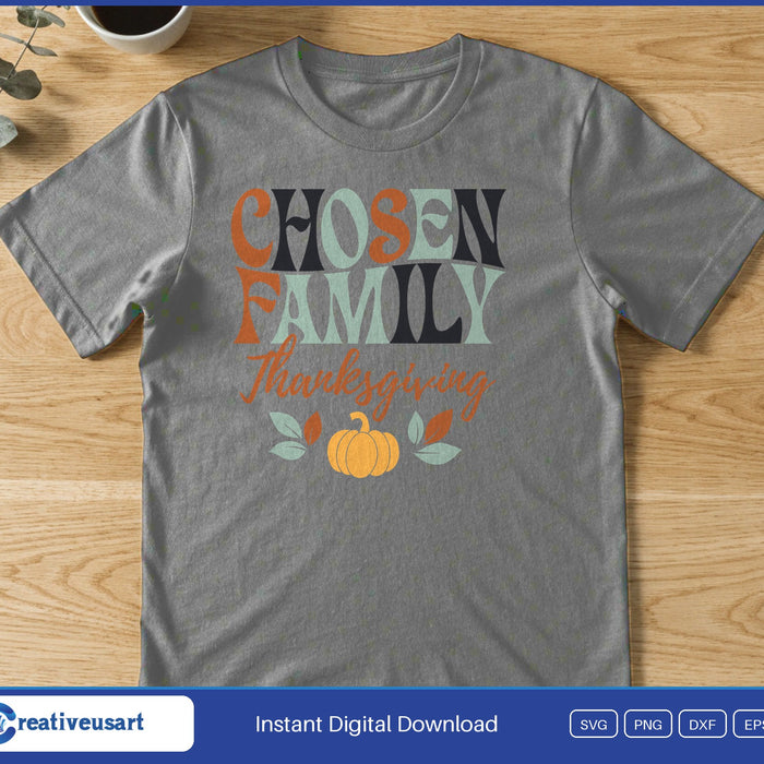The words Chosen Family Thanksgiving in retro letters above a small pumpkin and leaves, on a gray t-shirt