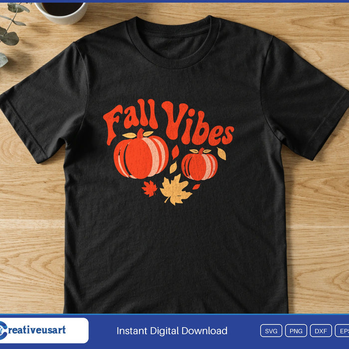 Two orange pumpkins with fall leaves under the words Fall Vibes in red, on a black t-shirt