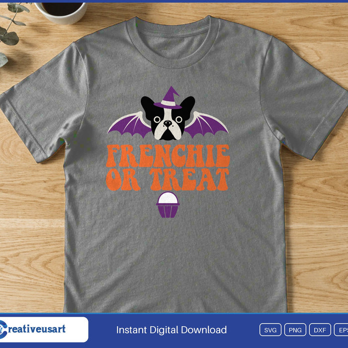 A French bulldog in a witch hat with purple bat wings above the words Frenchie Or Treat and a cupcake, on a gray t-shirt