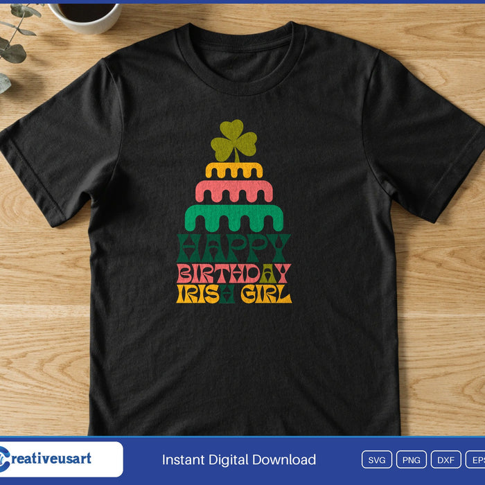 A layered birthday cake topped with a shamrock above the words Happy Birthday Irish Girl, on a black t-shirt