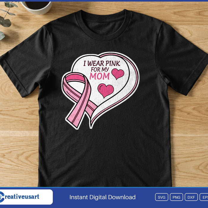 A white heart with a pink ribbon and small hearts around the words I Wear Pink For My Mom, on a black t-shirt