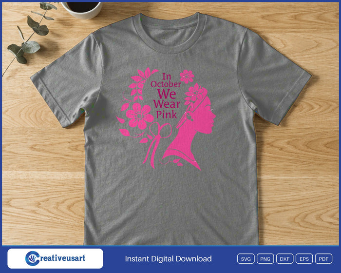 A woman's profile in pink with flowers in her hair and a ribbon, beside the words In October We Wear Pink, on a gray t-shirt