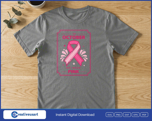 A pink ribbon inside a decorative pink frame, between the words In October and We Wear Pink, on a gray t-shirt