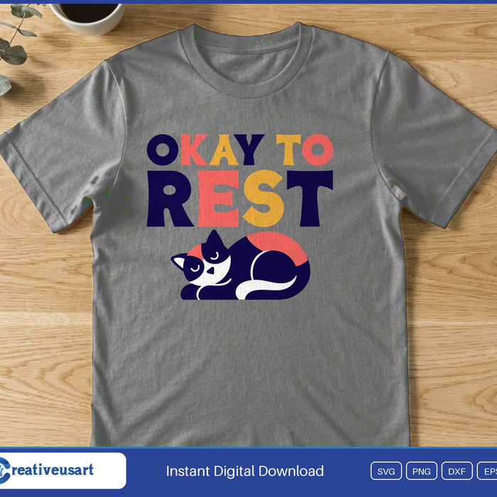 A black and white cat curled up asleep below the words Okay To Rest, on a gray t-shirt