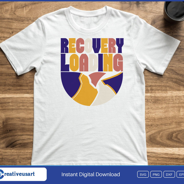 A mended bowl with a gold seam under the words Recovery Loading in bold colored letters, on a white t-shirt