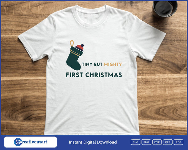 Tiny But Mighty First Christmas with a small stocking and knitted hat SVG printed on a white t-shirt
