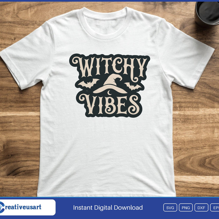 A badge with the words Witchy Vibes around a witch hat and small bats, on a white t-shirt